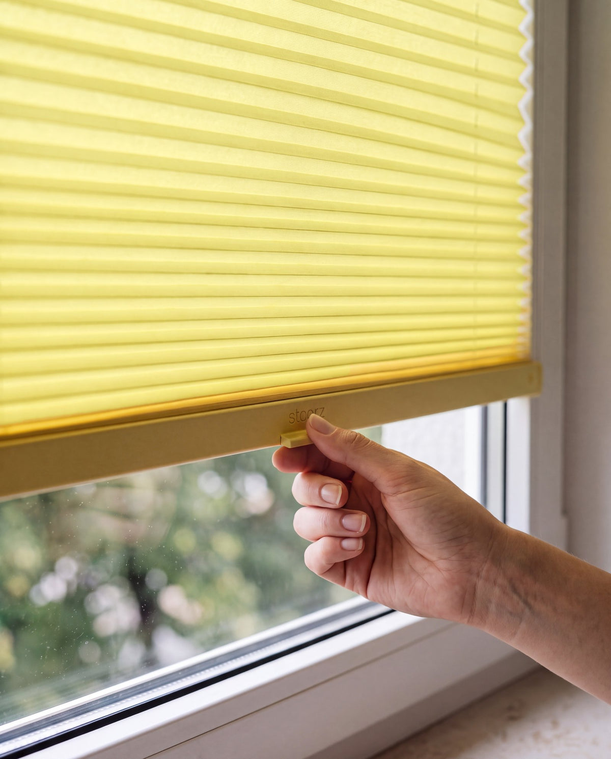Hand adjusting a Citron pleated blind by its handle