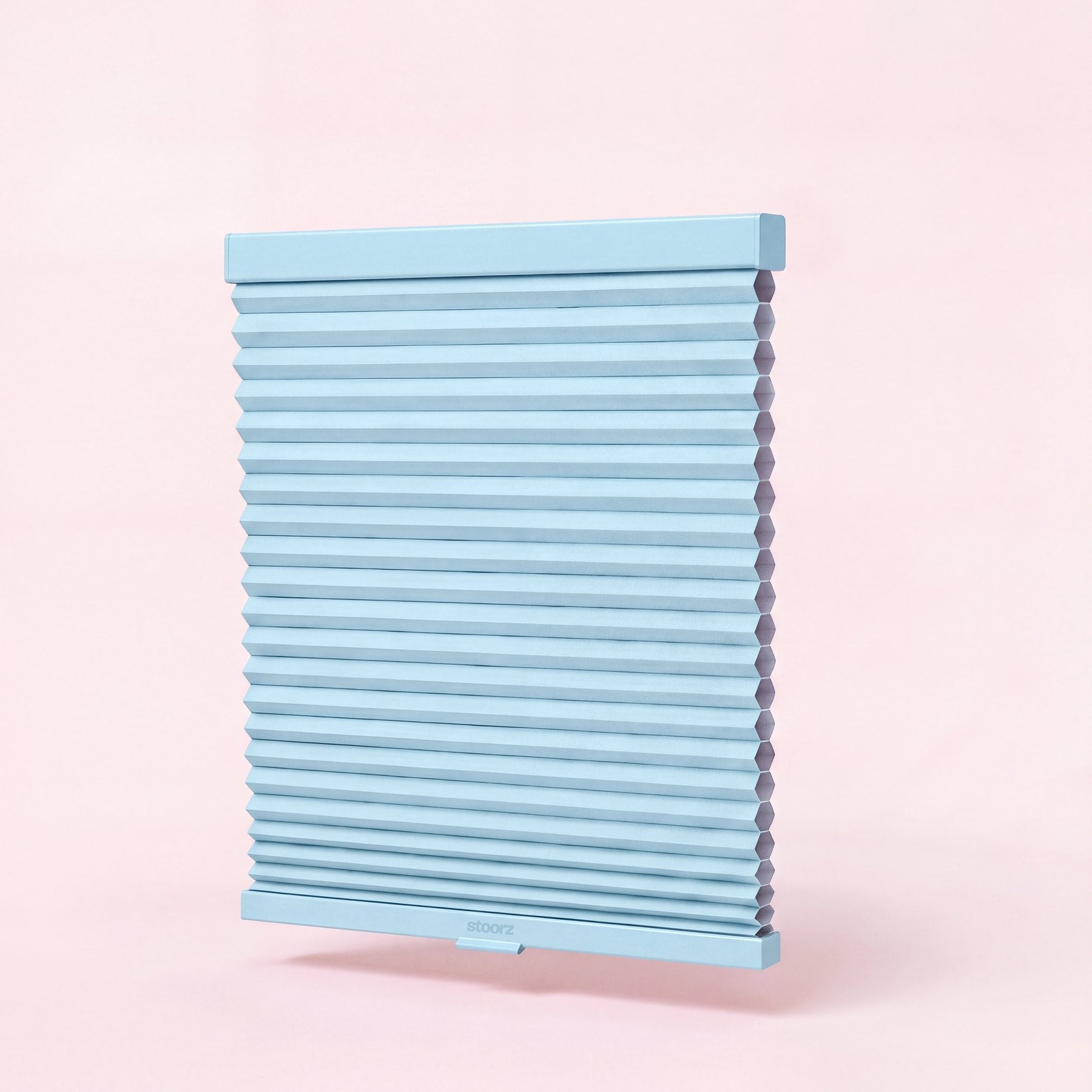 Store Stoorz avec son rail alu à bande adhésive, son tissu plissé et sa barre basse à poignée clipsable